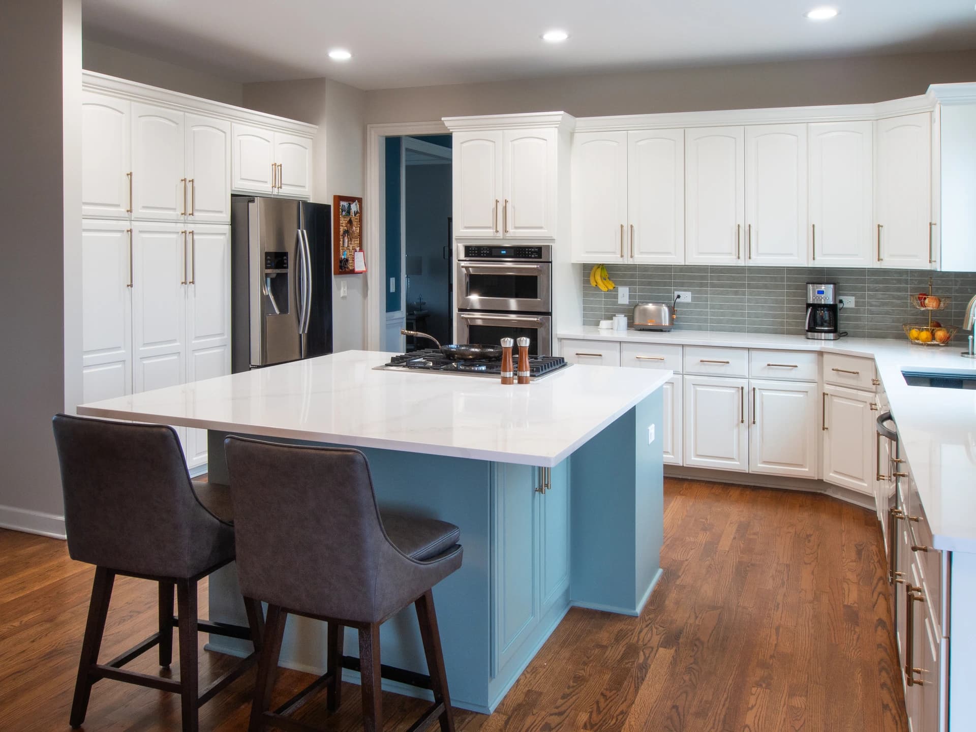 Large kitchen with white cabinets, blue island, and stainless steel appliances.
