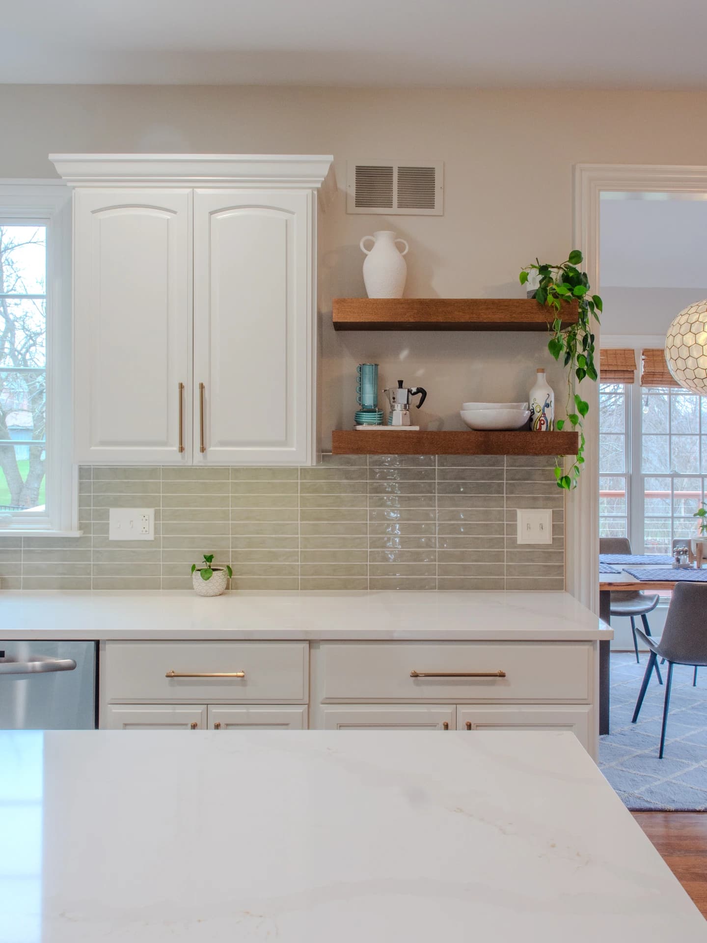 White kitchen cabinets with modern backsplash, subway tile countertops, gray accent wall.