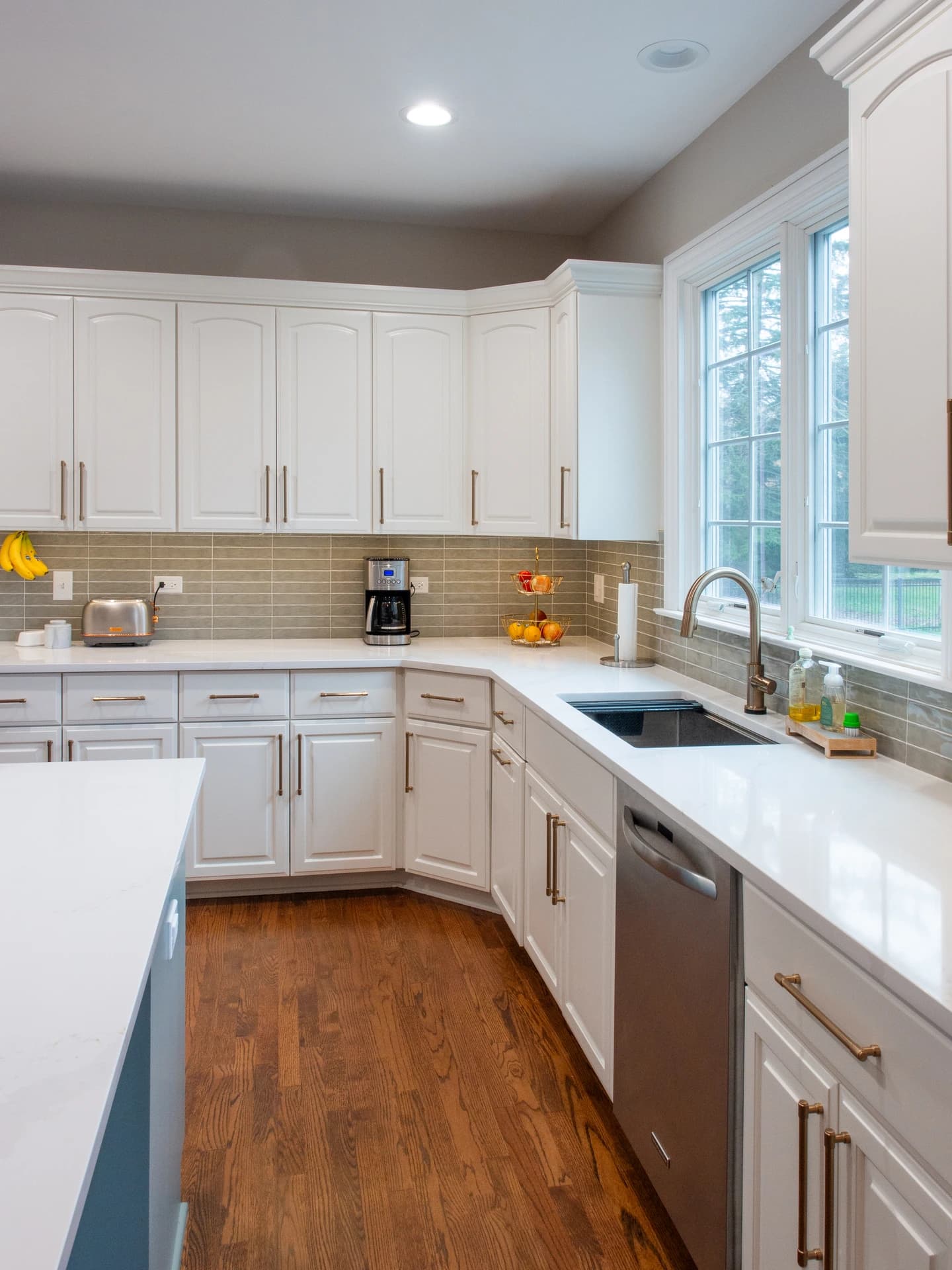 Modern kitchen with white cabinets, stainless steel appliances, and wooden flooring.