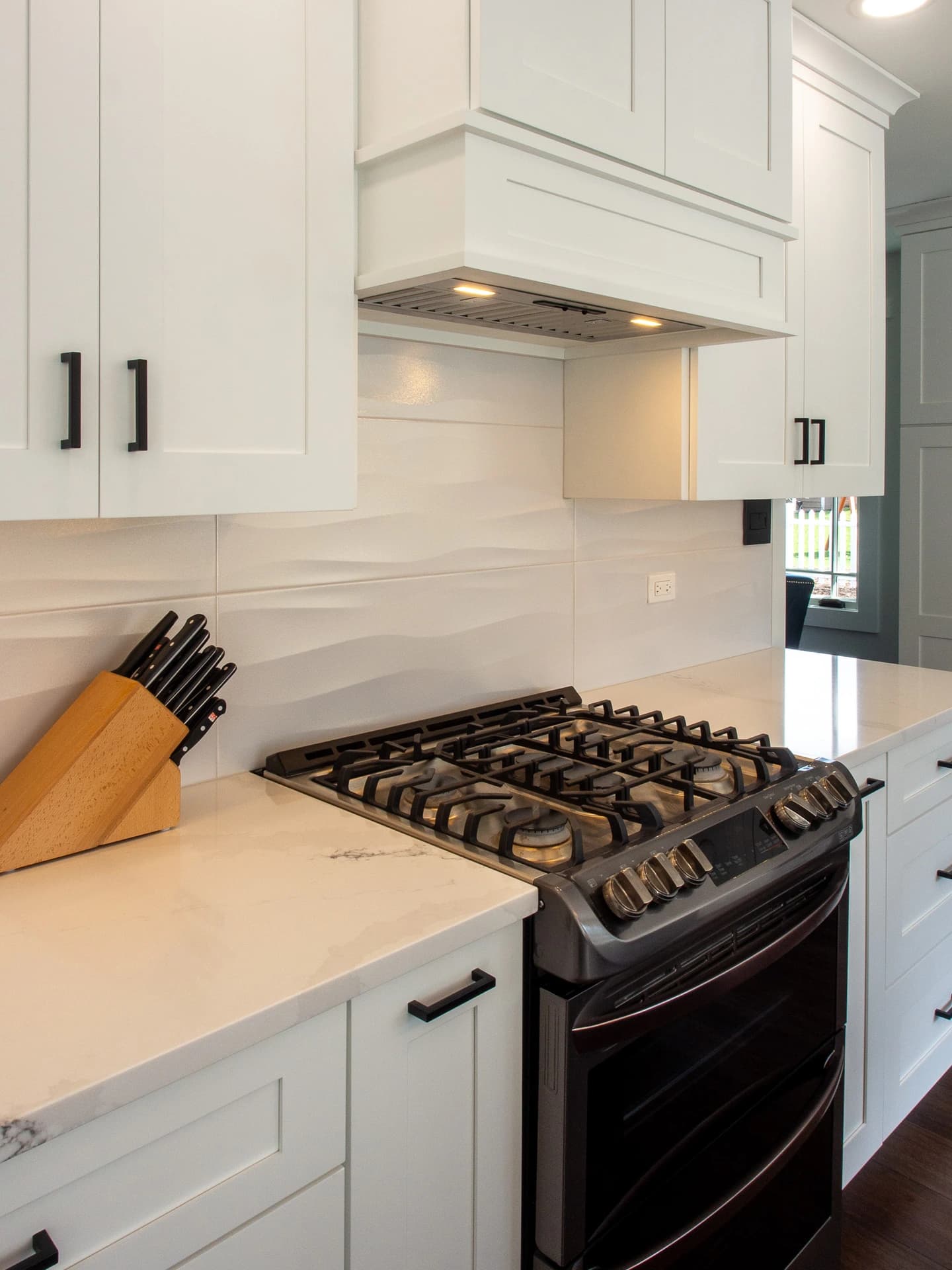 White cabinets, black countertops, stainless steel appliances, modern backsplash.