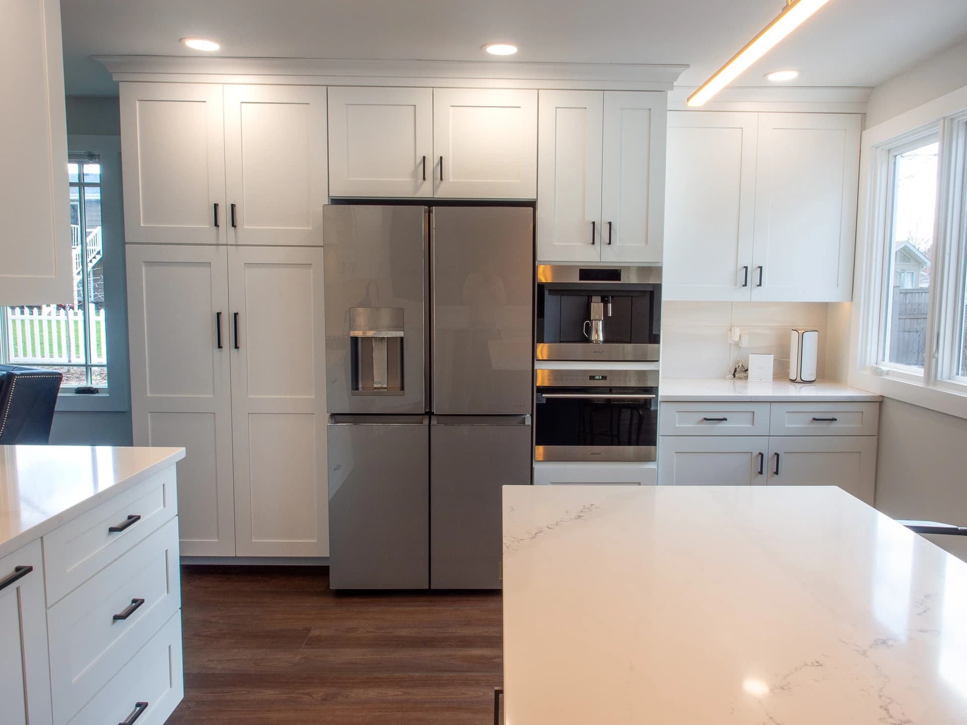 A modern, all-white kitchen with dark cabinetry, stainless steel appliances, and black countertops.