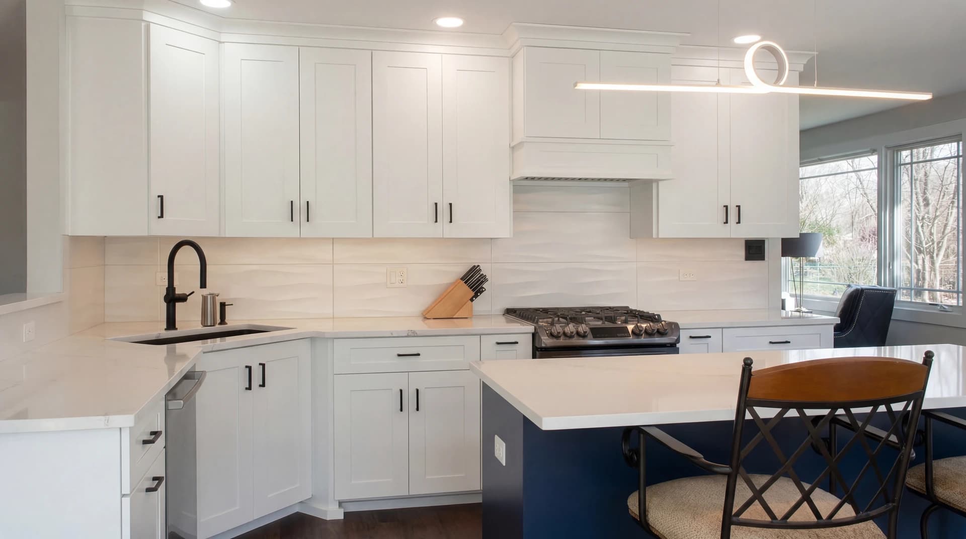 A modern kitchen with white cabinets, a center island, and stainless steel appliances.