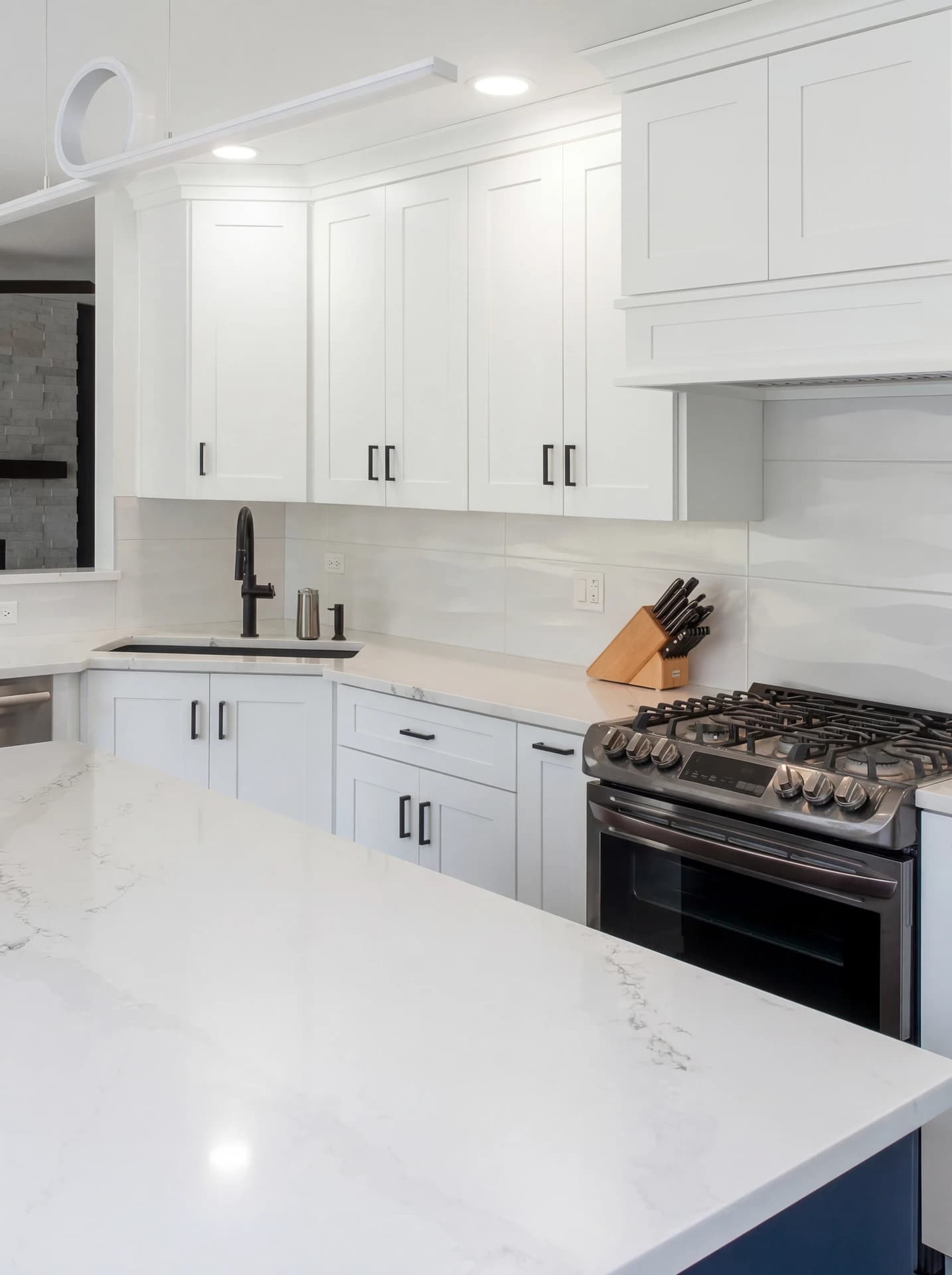 Clean, white kitchen with marble countertops and cabinets.