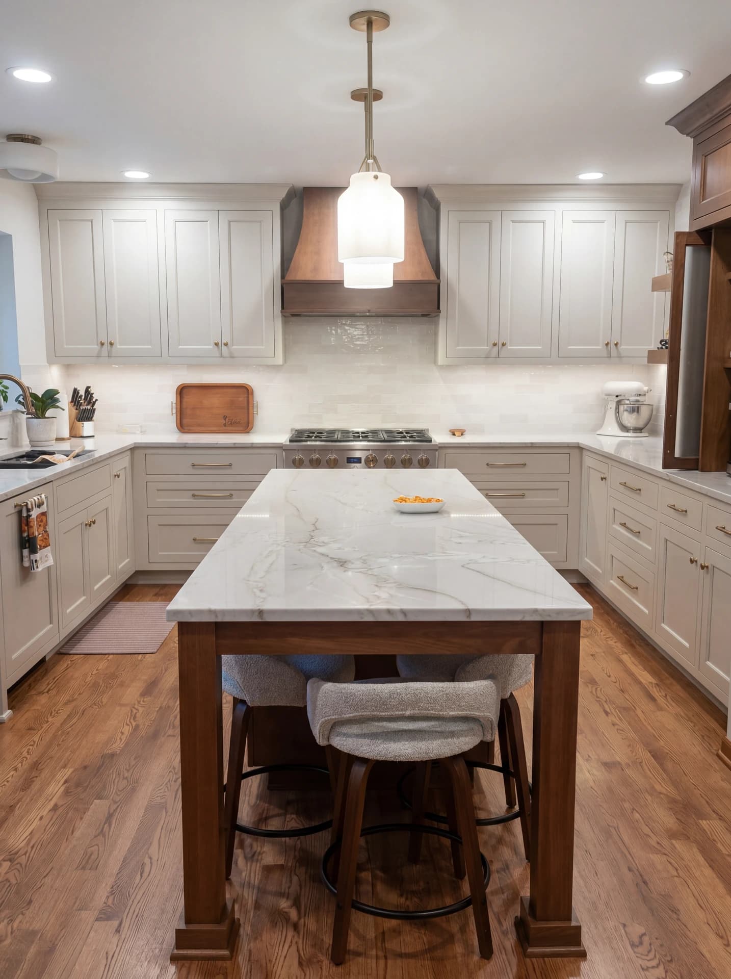 Elegant kitchen with marble countertops, wood floors, and white cabinets.