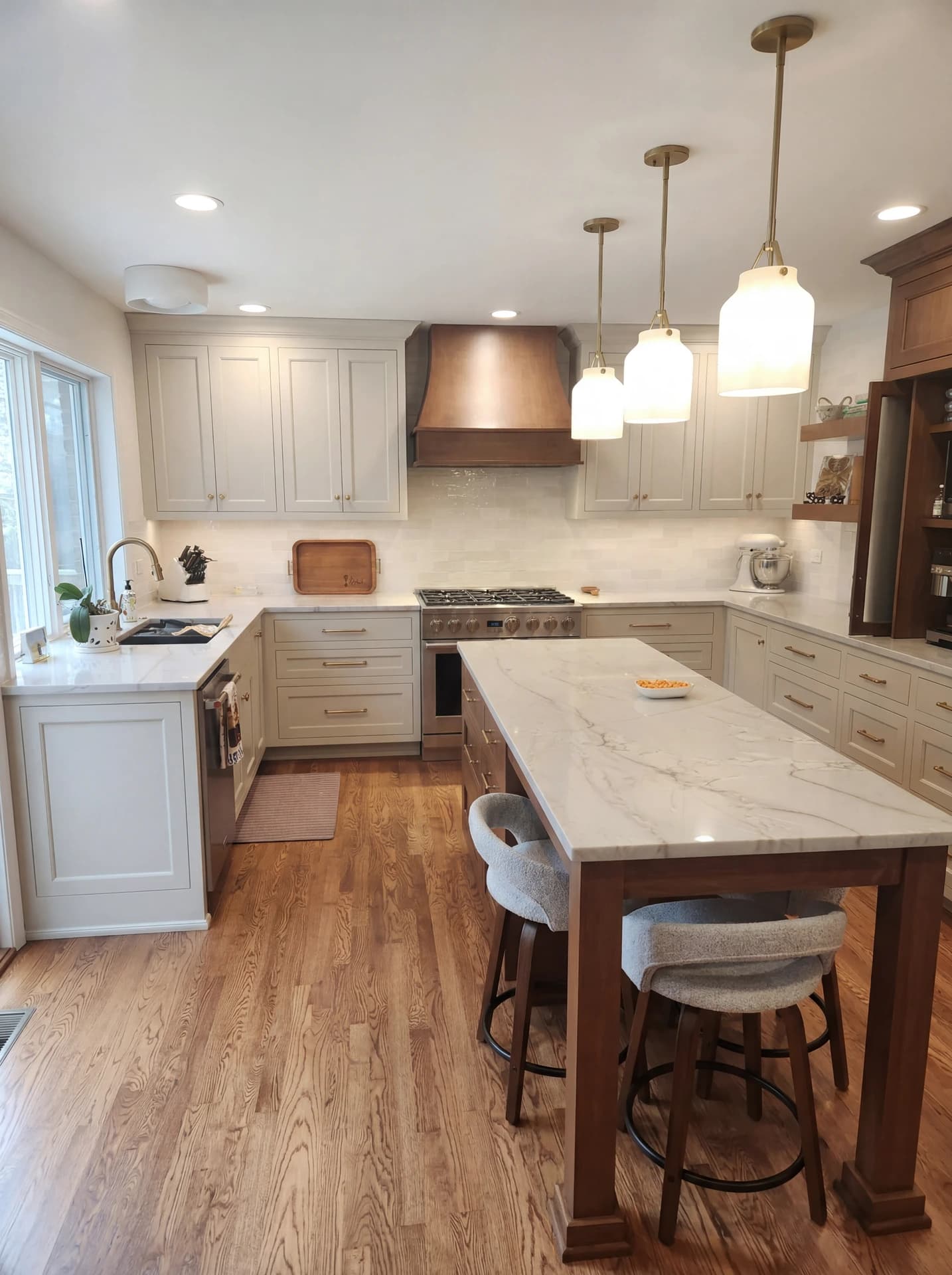 Modern kitchen with white cabinets, marble countertops, and stainless steel appliances.