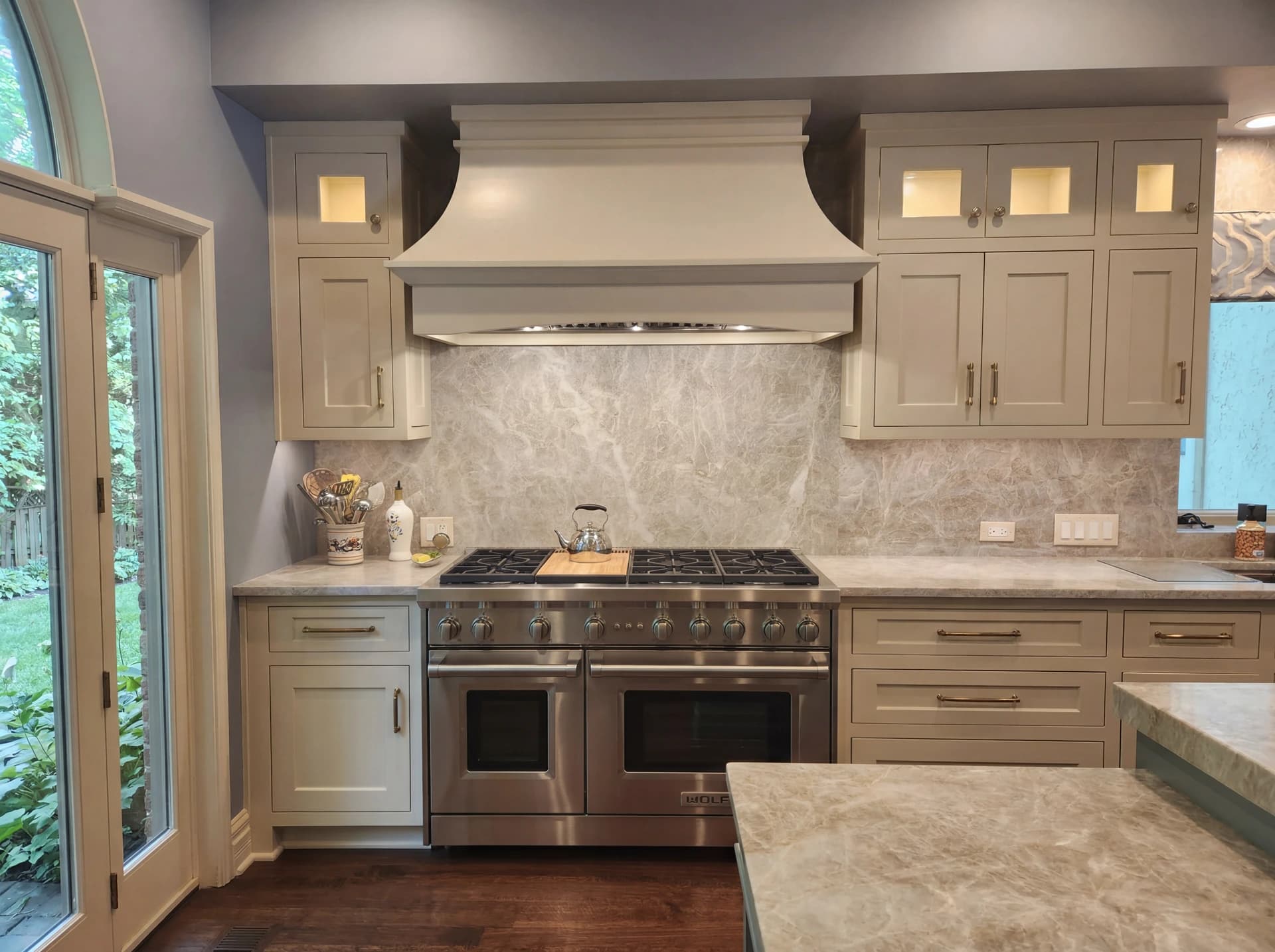 Large kitchen with gray cabinets, white countertops, and marble backsplash.