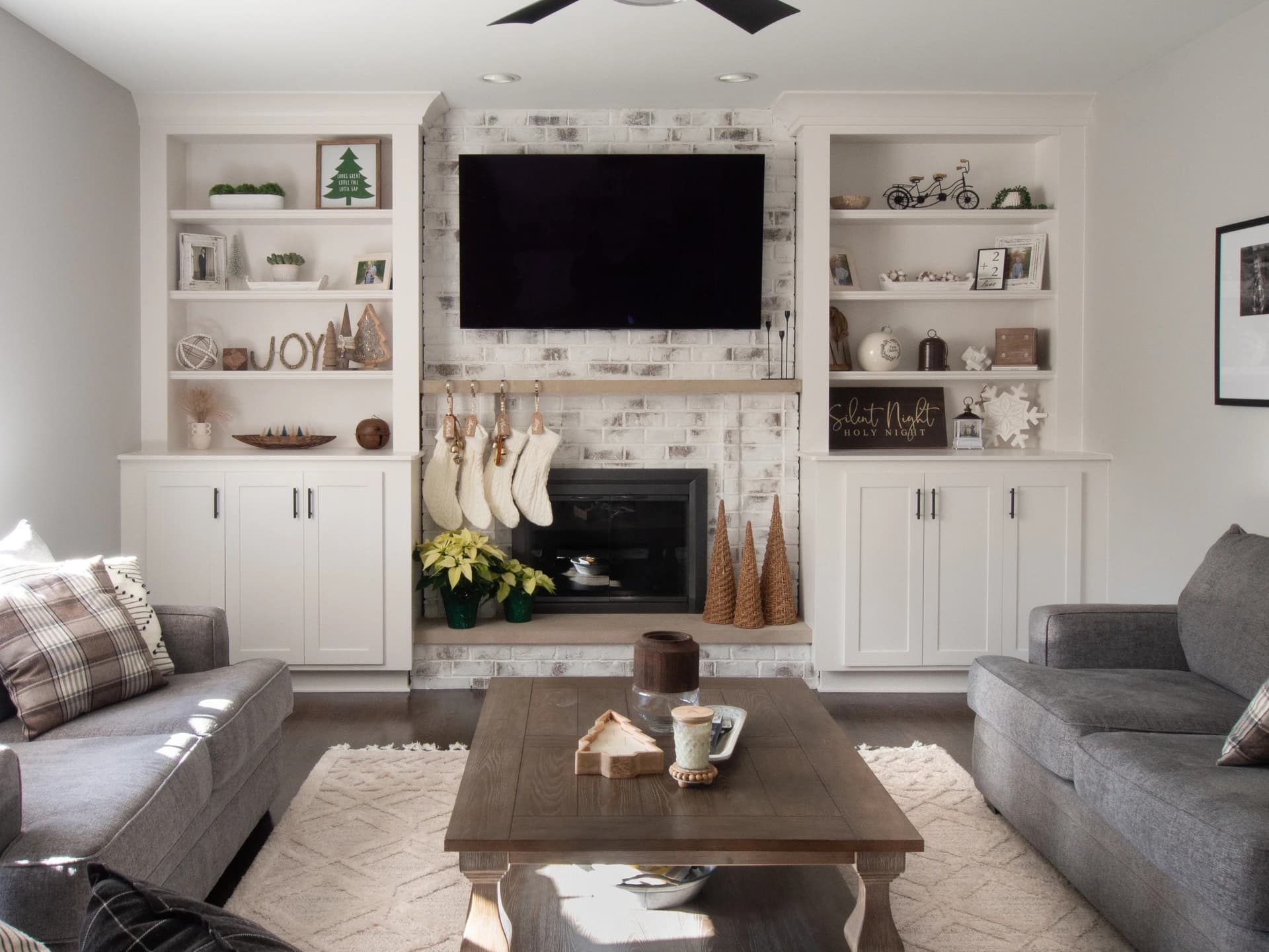 Modern living room with neutral tones, white shelves, black fireplace, and decorative elements.
