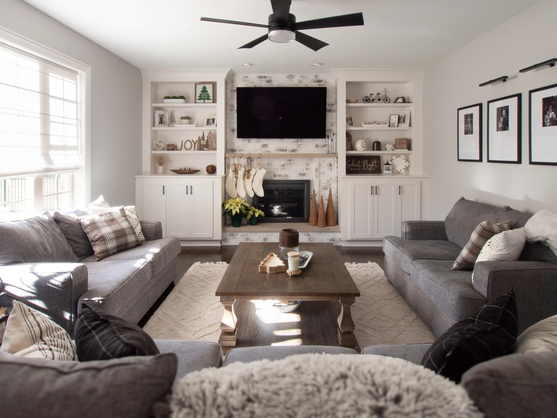 Modern living room with gray sectional sofa, hardwood floors, gray wall, and ceiling fan.
