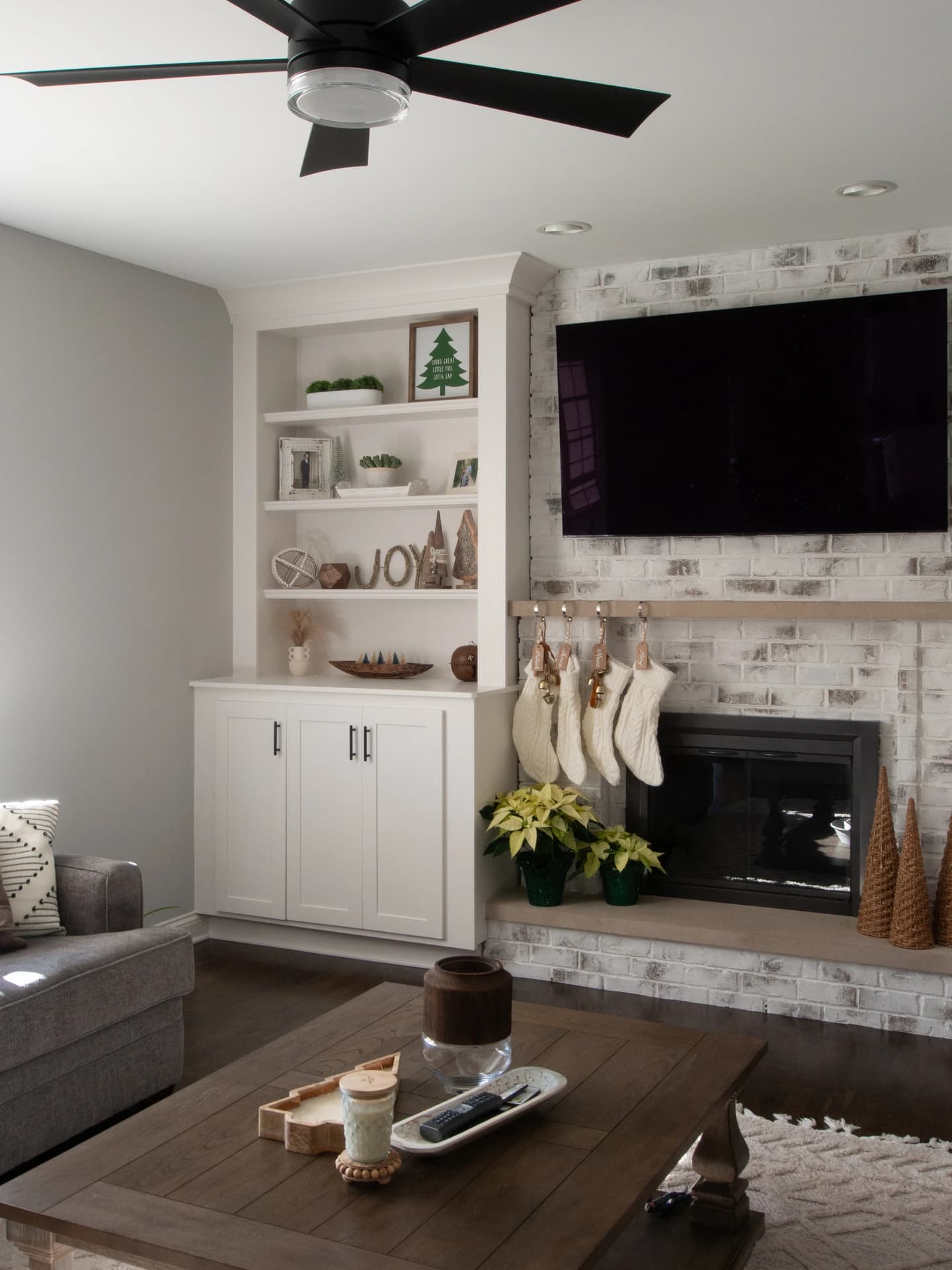 Spacious living room with fireplace, brick walls, white ceiling, ceiling fan, dark wood floors,