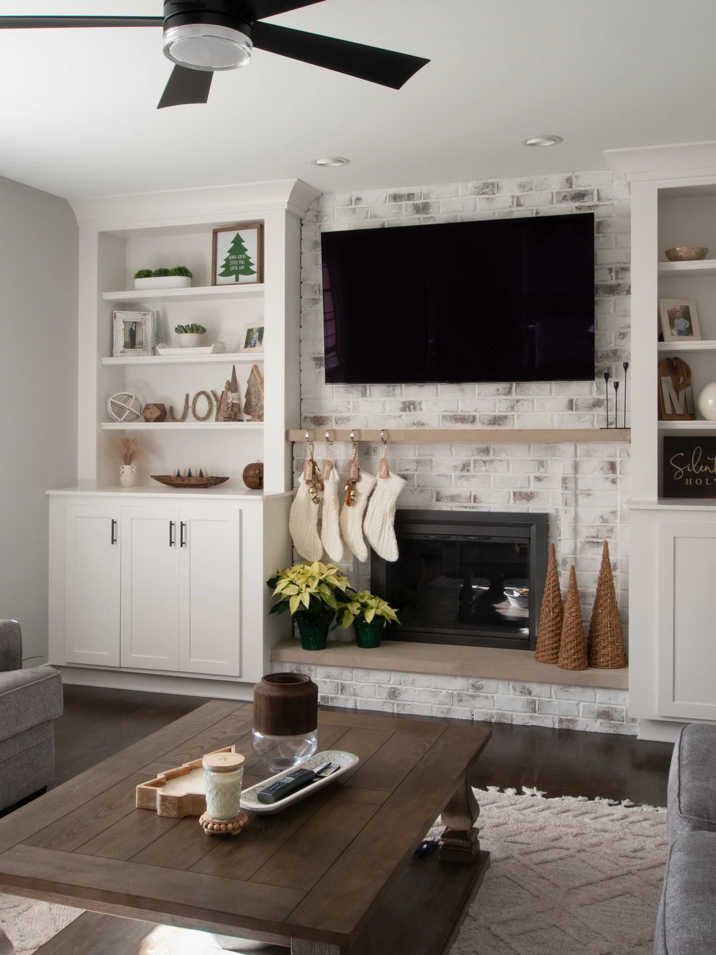 Contemporary living room with gray and white brick fireplace, white walls, and dark wood floors.