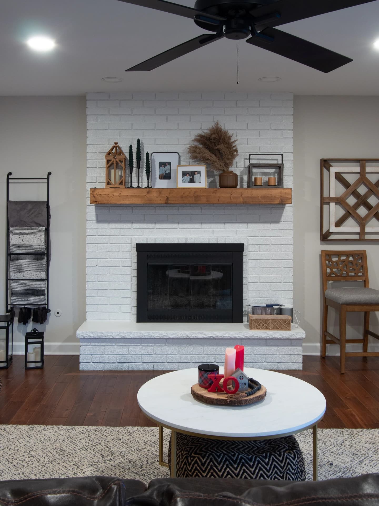 Modern living room with white fireplace, wooden shelves, and brick mantle.